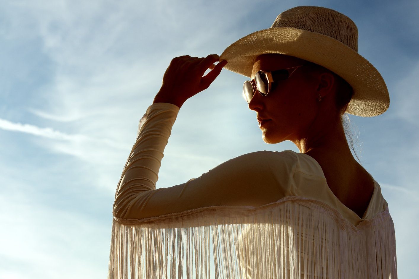 Cowgirl in Cowboy Hat Silhouette over Blue Sky Background.