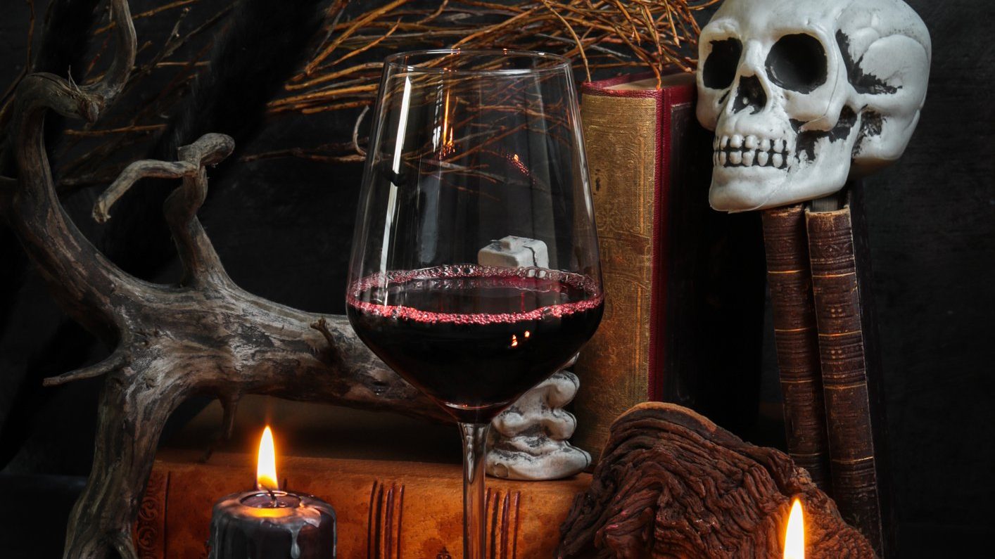 Tablescape with black candles, a skull and glass of red wine