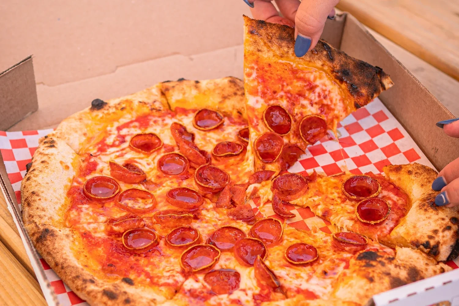 Hand pulling slice of pizza out of box